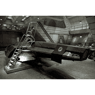 A sci-fi fighter jet with a ladder attached to it in a docking bay.